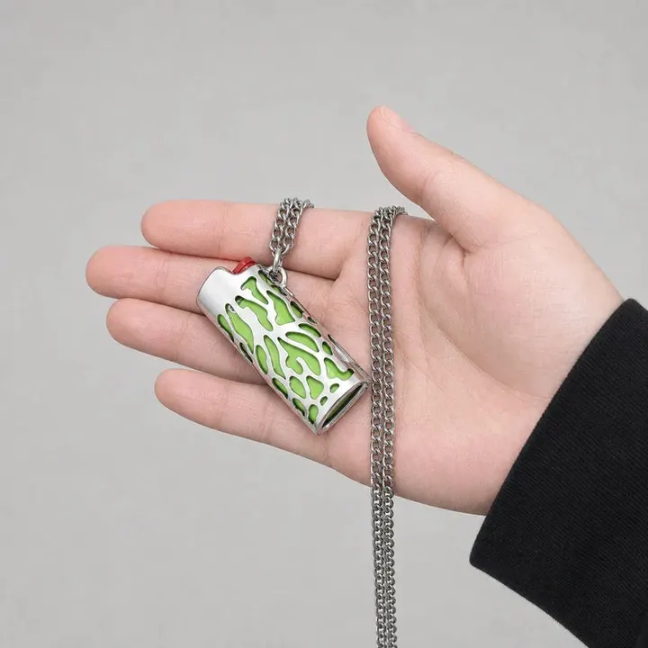porta-isqueiro-bic-mini-j5-colar-chama-verde-na-mao - Porta-isqueiro BIC Mini J5 com colar chama verde segurado na mao, mostrando tamanho e acabamento.